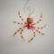 A vibrant red and gold beaded spider ornament with sparkling accents and decorative beads Handcrafted wire legs create a festive, look.